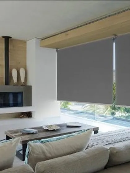 A repeat image of the grey roller blinds, showing their effectiveness in a contemporary living space with large windows.