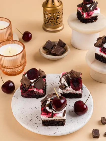 Mini black forest style pastries, topped with fresh cherries and chocolate shavings, creating a tempting dessert spread.