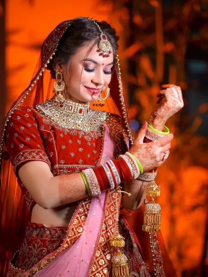 A classic bridal pose, showing the bride adjusting her kalire. This captures a traditional element in a beautiful way.