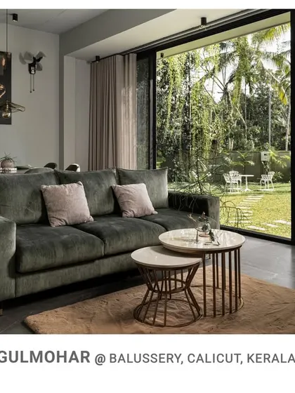 The living room at Gulmohar, with its comfortable green sofa and nested coffee tables, opens directly onto the lawn, creating a perfect blend of indoor comfort and outdoor space.