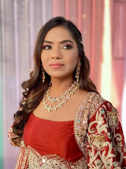 A traditional Haldi look for Aanchal. The makeup features a warm, smokey eye and a flawless base to complement her rich, rust-colored outfit.