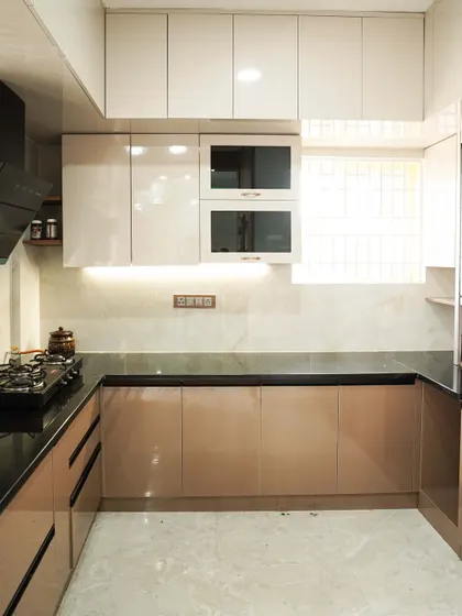 This U-shaped kitchen uses a dual-tone scheme with beige and white glossy cabinets. The layout maximizes counter and storage space, making it ideal for those who love to cook and need an organized environment.