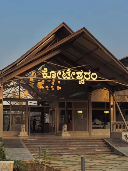 The grand entrance of the Koteshwaram restaurant in Devanahalli. The design features a modern interpretation of a traditional gabled roof structure, creating an impressive and welcoming facade.