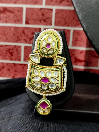 A close-up of a modern kundan earring with pink and green enamel work. This rental piece is perfect for adding a pop of color.