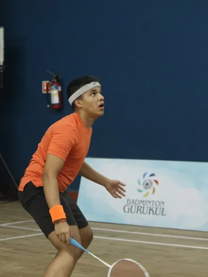 A young player watches the shuttlecock intently, preparing for a high shot during the Gautam Thakkar Memorial Championship.