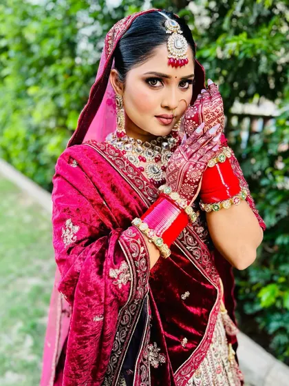 This portrait captures the harmony between the bride's expression and her henna. The detailed mehndi work on her hands and fingers beautifully frames her face.