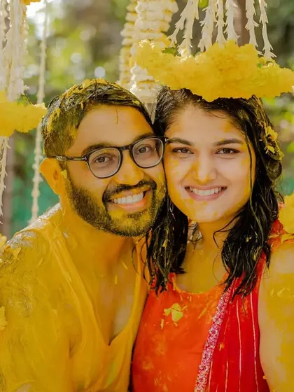 The happy couple posing for a photo after their fun-filled Haldi ceremony, covered in turmeric and smiles.