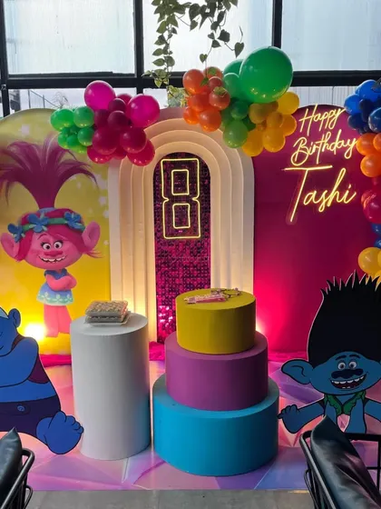 A vibrant Trolls themed birthday party with large cutouts of Poppy, Branch, and other characters.