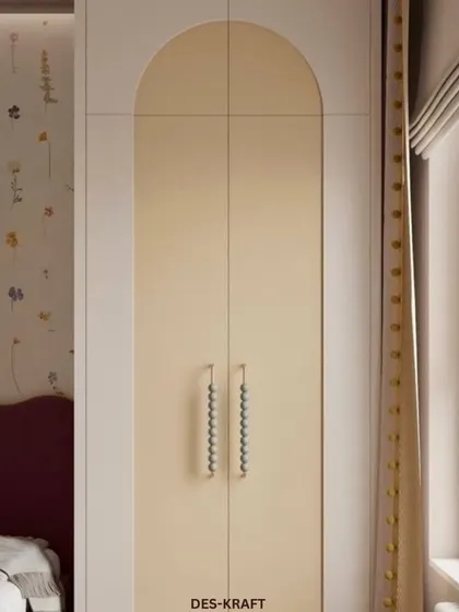 A detail of the arched wardrobe doors with unique beaded handles, adding a touch of bespoke charm to the room's soft and pastel aesthetic.