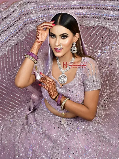 A model in a lavender lehenga, showcasing a modern and chic bridal or reception look. This demonstrates the versatility of our students' skills beyond traditional red and pink.