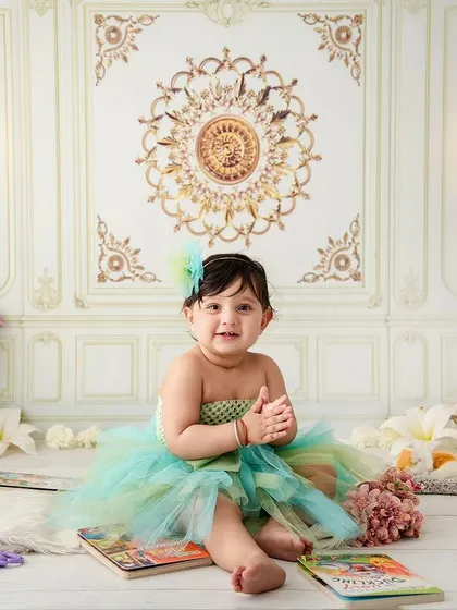 A happy, clapping little girl, enjoying her storybook time in a beautiful, classic studio setting.