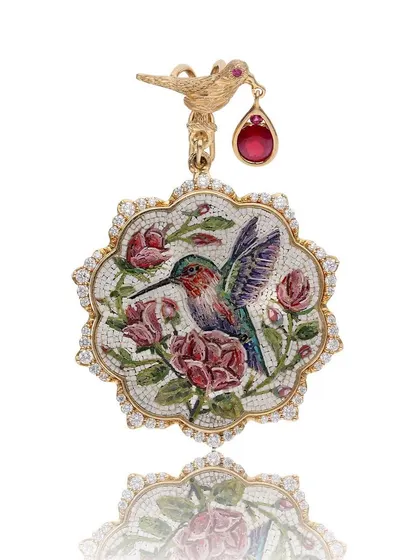 A detailed view of the micromosaic hummingbird and roses pendant. Handcrafted in 18k gold, this piece combines the delicate art form with the brilliance of natural diamonds and a deep red Mozambique ruby.