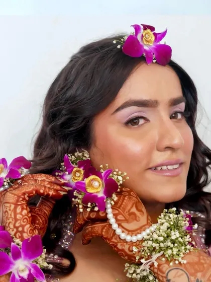 A beautiful look for a Haldi or Mehendi ceremony. The makeup is subtle and elegant, with a focus on natural radiance to complement the floral jewelry.