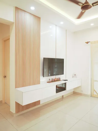 A bright and minimalist living room with a floating TV unit against a wall with light wood paneling. The space feels open, clean, and filled with natural light.