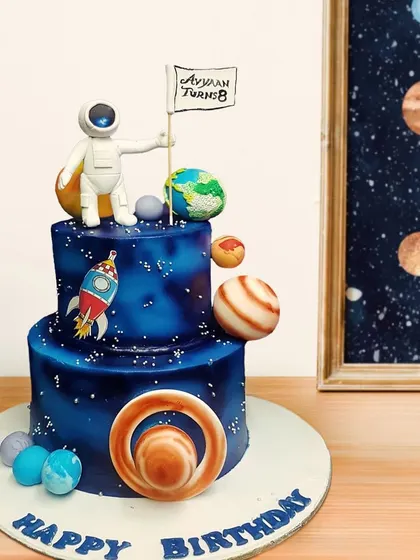 3, 2, 1, blast off! This space-themed cake is perfect for a little astronaut's birthday. It features a two-tier galaxy design, edible planets, a rocket ship, and an astronaut planting a personalized flag.
