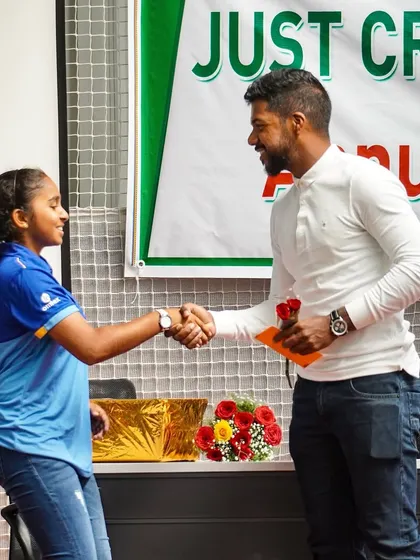 A young female cricketer receives an award from Indian fast bowler Varun Aaron at one of our academy events.