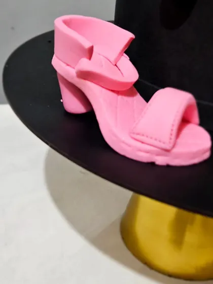 A tiny, edible pink high-heeled shoe, handcrafted as part of a makeup and fashion-themed cake. Creating miniature, realistic items like this is one of my specialties.