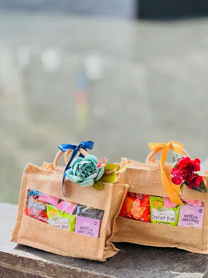 Two jute bag hampers filled with snacks, sitting on an outdoor ledge. These are perfect for informal corporate get togethers or team outings.