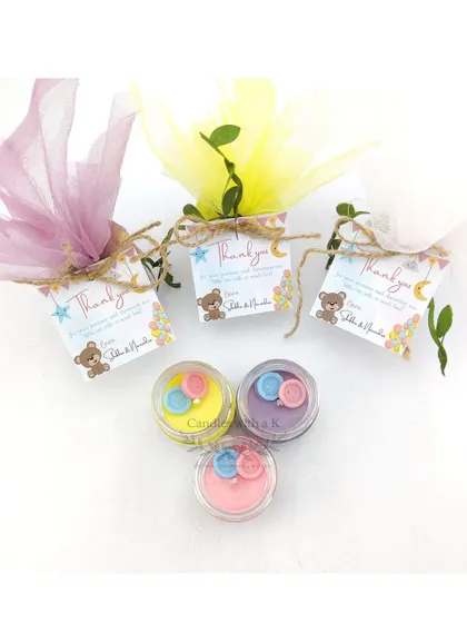 A trio of the button-topped mini jar candles, showcasing the different color and scent combinations available for baby showers.