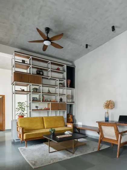 The family space is made cozy with wooden accents, a neutral grey textured background, and a pop of warm color from the yellow sofa.