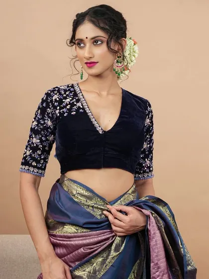 A deep V-neck velvet blouse with embroidered sleeves, paired with a beautiful silk saree.