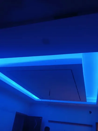 A living room ceiling with vibrant blue LED cove lighting, creating a dramatic and modern effect.