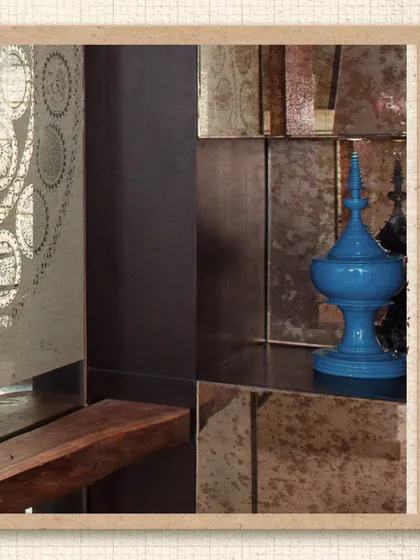 A custom shelving unit at the Modi Residence, featuring antiqued mirror panels and a pop of color from a ceramic vase. This project was an exploration in mixing materials and finishes to create a unique, personal space.