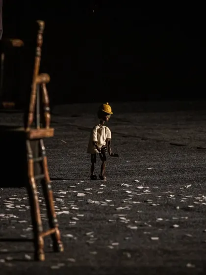 A solitary marionette stands on a stage littered with confetti, creating a poignant and atmospheric image from 'Il Fil'armonico'.