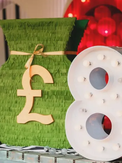 The decor included fun props like this giant money bag piñata and a light-up number '8', perfect for photo ops and adding to the Monopoly theme.