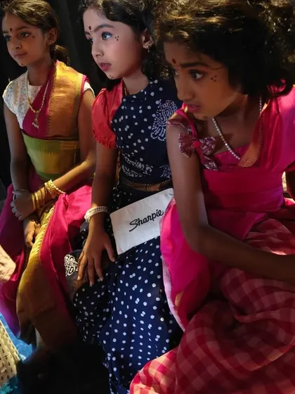 Young actresses waiting backstage, their expressions a mix of anticipation and focus. This candid moment captures the pre-show jitters and excitement.