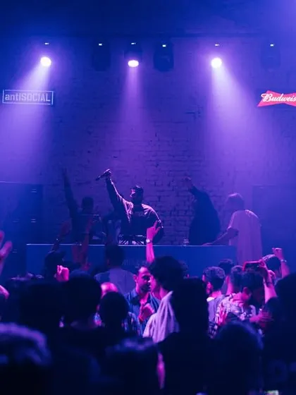 The crowd with their hands up under purple lights. A moment of pure energy and nostalgia during the Back to School party.