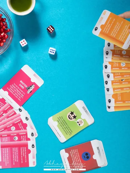 A vibrant and playful flat lay for an educational card game. The bright blue background and scattered game elements create a sense of fun and engagement, inviting people to learn more.