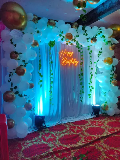 A different perspective of the white drape and neon sign backdrop, showing the full effect of the balloon arch.