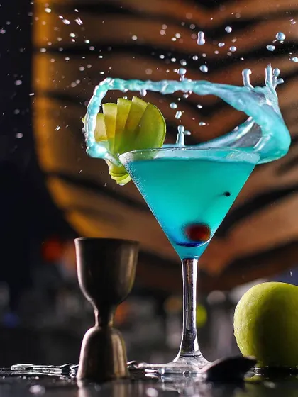 A dynamic splash of a blue cocktail, frozen in time with perfect lighting and composition. This is a prime example of high-energy beverage photography that we love to feature.