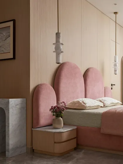 The custom-designed bed in the kid's room features an arched, upholstered headboard that adds a touch of whimsy. Sculptural pendant lights hang on either side, providing soft, ambient lighting.