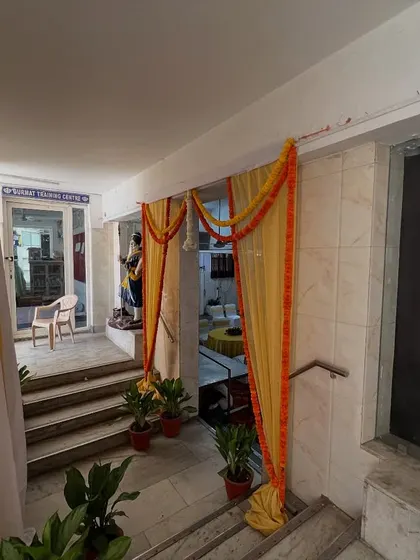 A simple yet elegant entrance decoration using yellow fabric drapes and marigold flower strings, suitable for smaller events or functions.