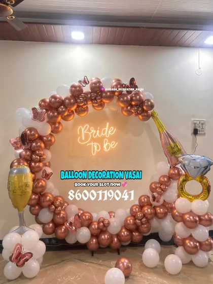 Celebrate the bride-to-be with a fun and trendy setup. This rose gold and white balloon ring arch, complete with a neon sign and playful props, is perfect for party photos.