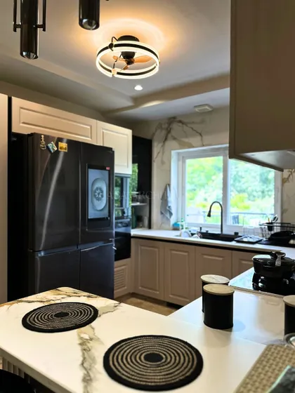 This kitchen view highlights the practical and stylish island with an induction cooktop, set against a backdrop of modern cabinets and a large window that brings in natural light.