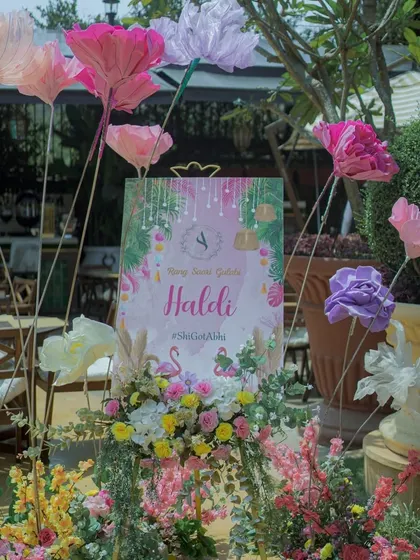 The welcome sign for a pastel-themed Haldi, decorated with large paper flowers. The soft colors and flamingo motif set a chic and playful tone for the event.