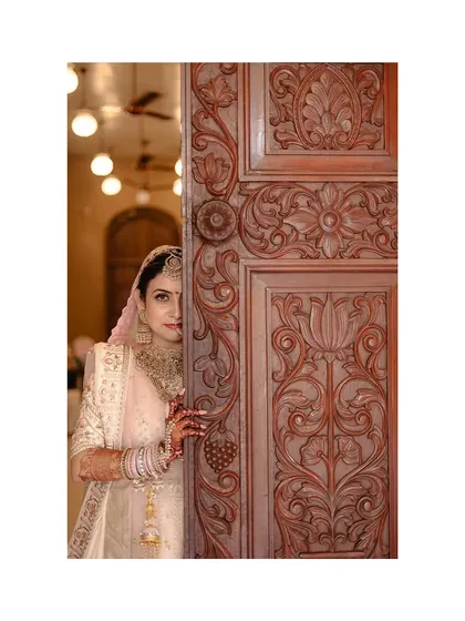 A beautiful bridal portrait, with the bride peeking from behind an intricately carved door, just moments before the ceremony.