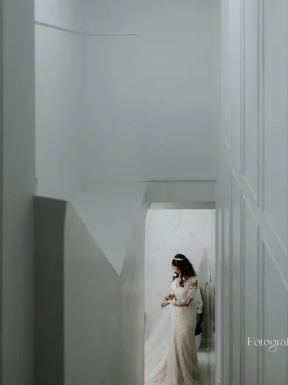 An artistic shot of the bride in her white gown, seen from above as she walks through a minimalist white hallway.