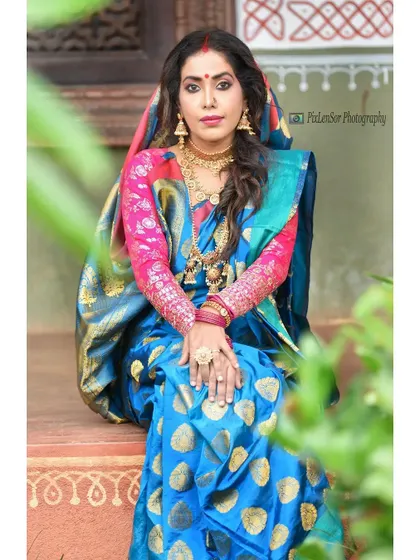 An actress styled in a beautiful blue Bengali-style saree, paired with our traditional gold jewellery for a photoshoot.