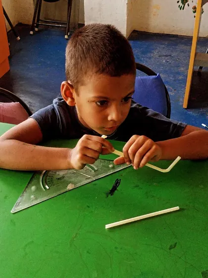 A student carefully works with simple materials to understand basic engineering concepts.