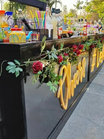 A side view of our elegant black wedding bar, adorned with red roses and a custom "Cheers" sign. We work with you to ensure the bar decor perfectly matches your theme.