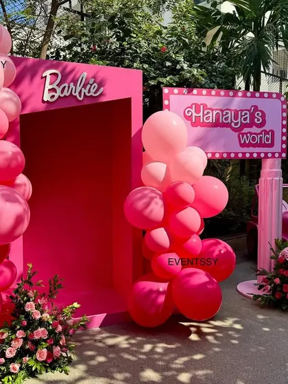 The entrance to 'Hanaya's World', a Barbie-themed party with a pink doorway, balloon arch, and a pink jeep.