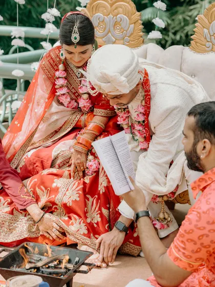 The couple participates in a fire ritual during their wedding ceremony, a serene moment of prayer and togetherness at the Leela Palace Bangalore.