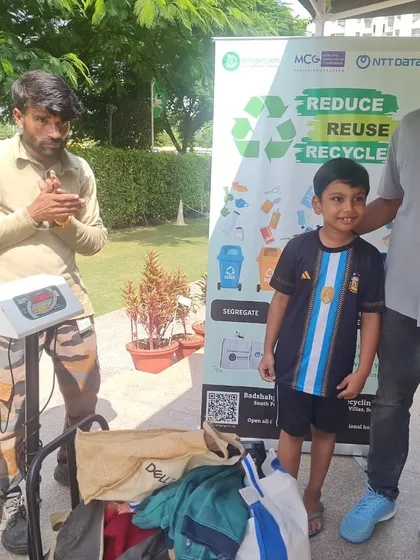 A father and son proudly stand with the dry waste they've brought for recycling at the school collection drive.