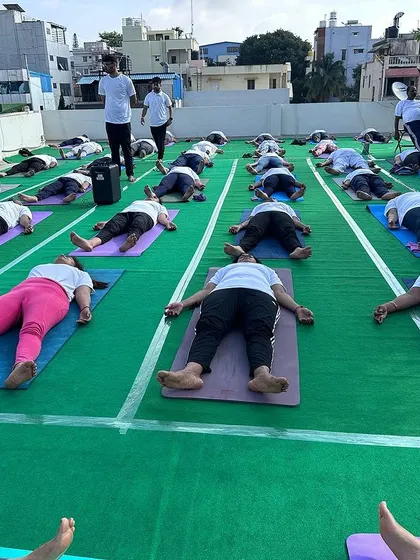 Students in Savasana (Corpse Pose) during a rooftop yoga session in Bengaluru. This moment of deep relaxation is an essential part of our practice, allowing the body and mind to integrate the benefits of the asanas.