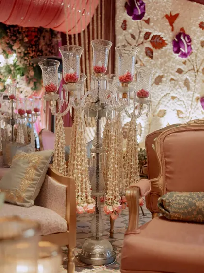 A detail shot of a classic candelabra decorated with delicate strings of jasmine. This is a perfect example of how we blend traditional floral work with elegant decor elements.