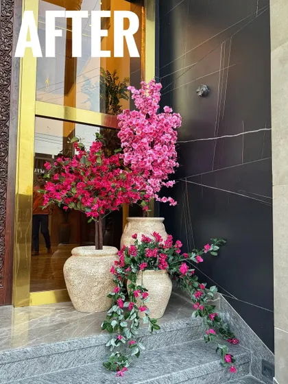 The "After" shot of the grand entrance. The combination of a real Bougainvillea and artificial pink blossoms in our textured pots creates a stunning, multi-layered floral display.